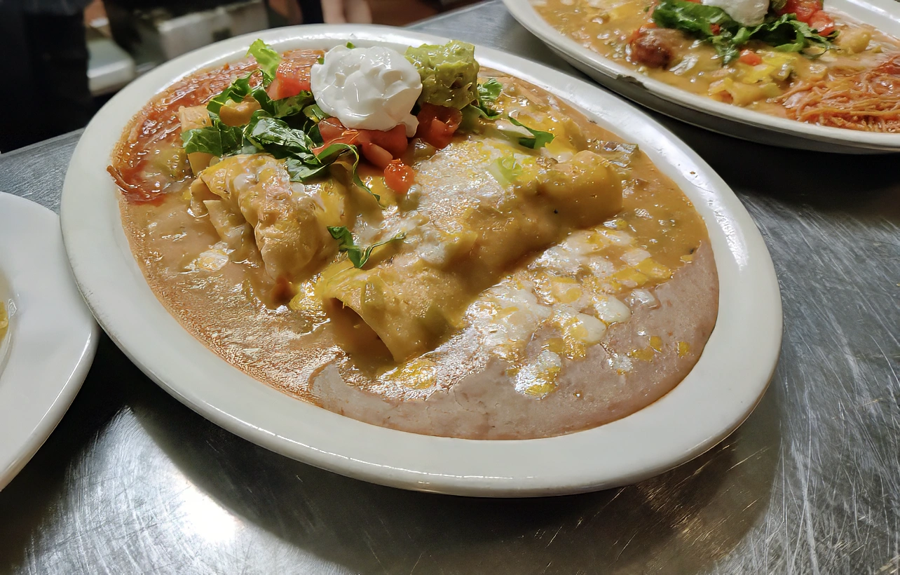 Comida Fiesta A refried bean burrito and two ground sirloin enchiladas smothered in chile verde or enchiliada sauce, topped with cheddar and Monterey jack cheese, lettuce, tomato, sour cream, and guacamole.