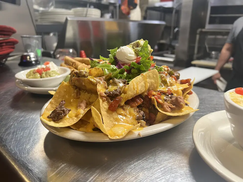 Mission Nachos A platter of corn chips loaded with refried beans, a choice of ground sirloin or shredded chicken, and smothered in chile verde.