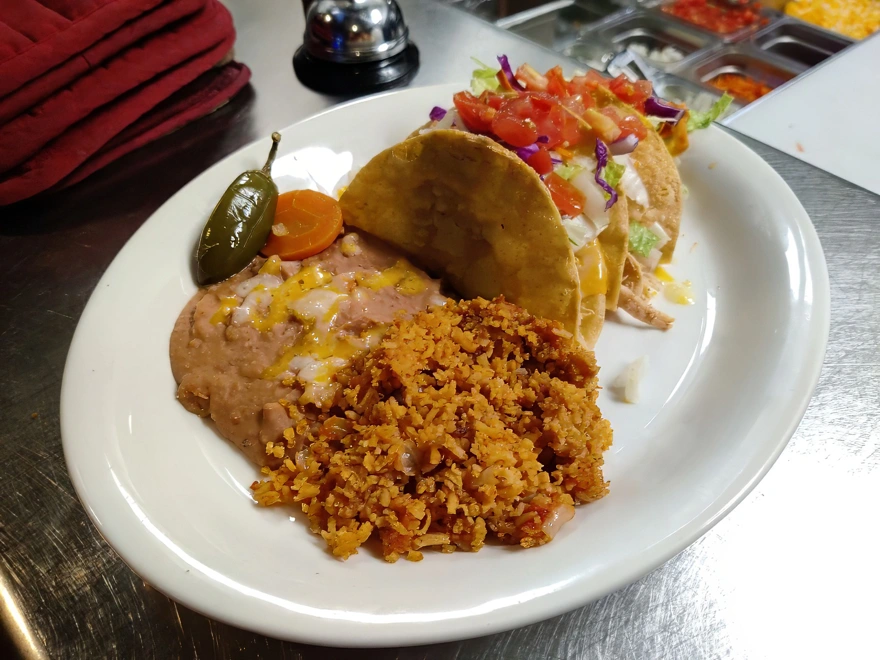 Taco Platter Three crispy tacos filled with hearty ground sirloin or tender shredded chicken, topped with cheddar and Monterey jack cheese, lettuce, tomato, and sour cream. Served with spanish rice or fideo and refried beans.